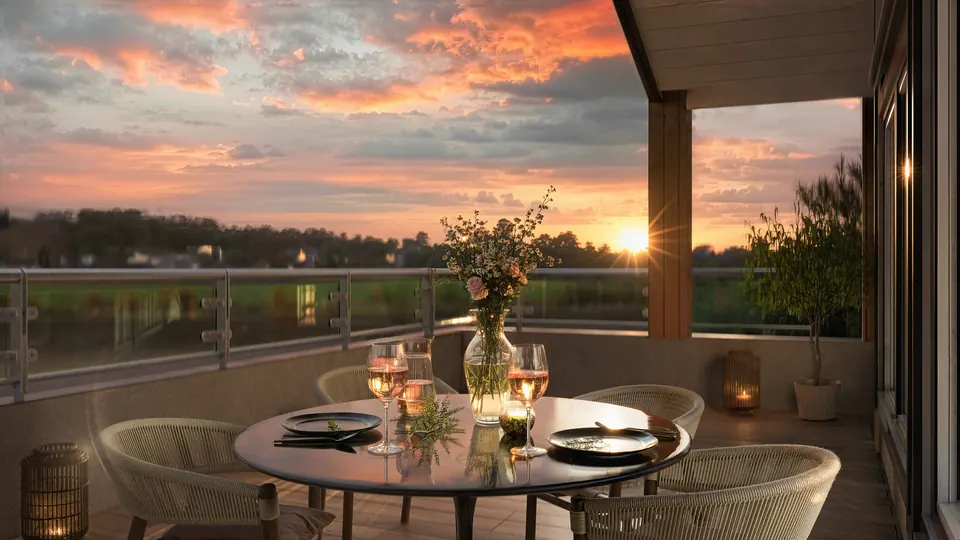 Dekket bord på en terrasse, med solnedgang over jordene